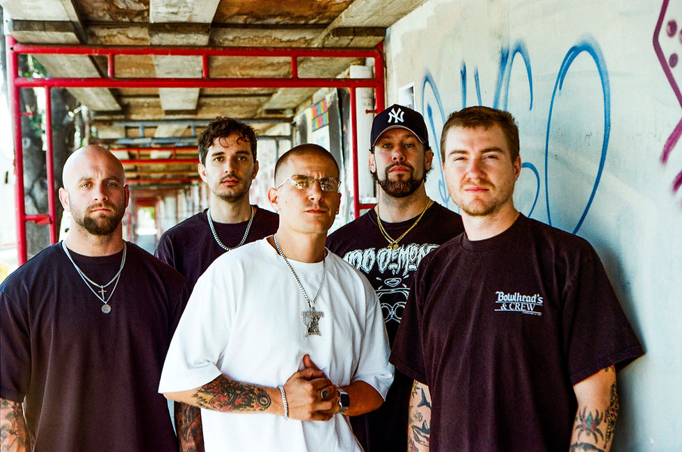 Five men pose in a graffiti-lined corridor, wearing dark shirts and chains; one white shirt reads Bowthead's Crew, serious mood