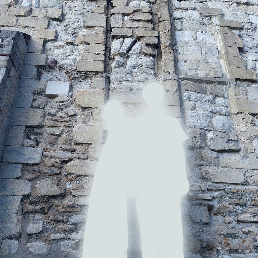 Two overexposed white figures stand in front of a weathered gray stone wall.