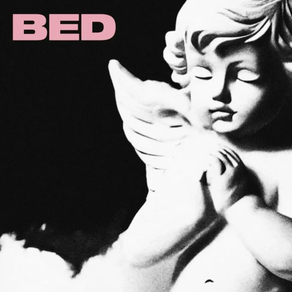 White cherub statue on black background with pink BED text, soft cloudlike base, serene mood.