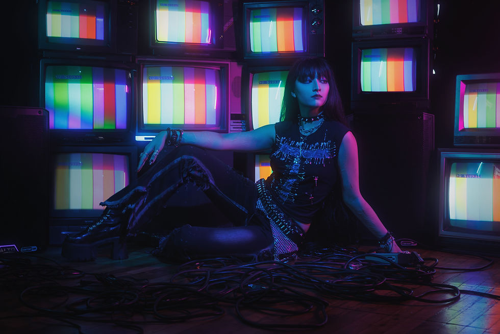 Woman in goth outfit lounges among stacked CRT TVs showing color bars and NO SIGNAL in neon blue-pink light.