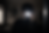 Person photographing self in a mirror with flash obscuring face. Dark room with photo collage and window. Moody, dim lighting.