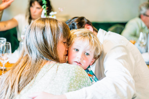 Lady kissing her young son and his dad hugging him