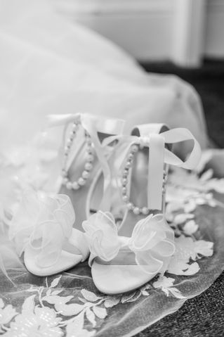 Black and white photograph of bridal shoes with pearls and bows