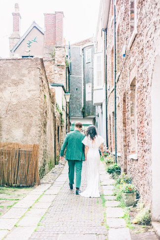 Bride and groom walking through rows of buildings