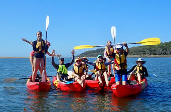 Family kayak group photo with kids staning on kayaks, rainign paddles