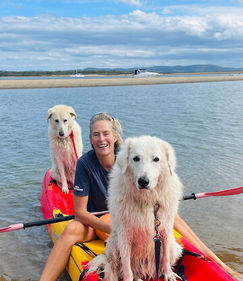 A smiling person in a kayak with a dog