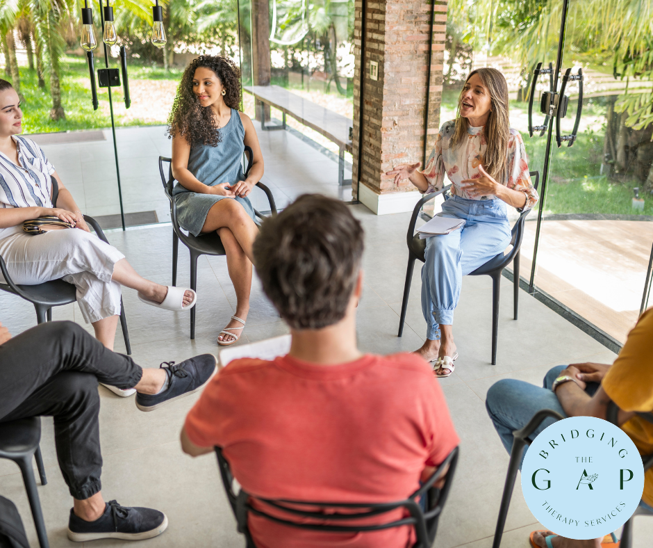 A group therapy session is underway where participants engage in an open discussion, guided by a facilitator, in a serene and modern setting.