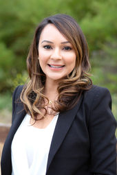 Female with black jacket and white blouse against an outdoor background