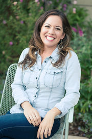 Personal branding photo of a woman smiling while sitting in a chair wearing blue jeans and lighter jean type shirt in San Diego. 