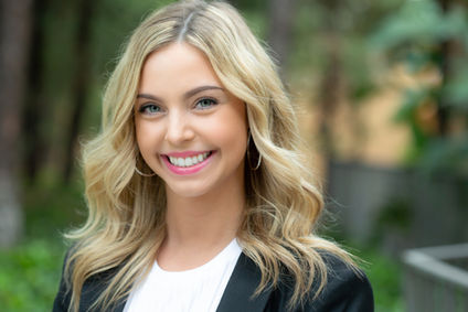 Woman with blond hair, black jacket and white blouse smiling for her branding photos in San Diego