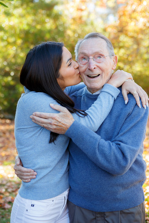 Adult grand daughter kissing grandfather on the cheek