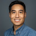 Smiling man in a blue shirt poses for a professional headshot, representing a team member from San Diego.