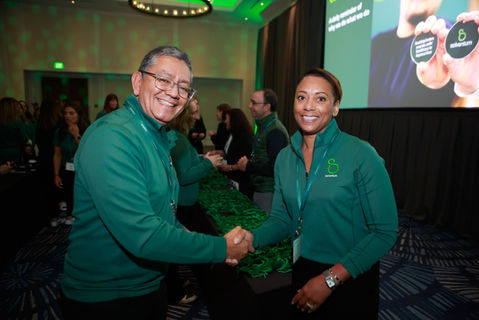 Man and woman shaking hands wearing Solventum green jackets