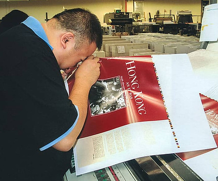 Using a magnifying eyepiece, Victor Cheong, the book’s designer, press checks the jacket of Hong Kong As It Was.