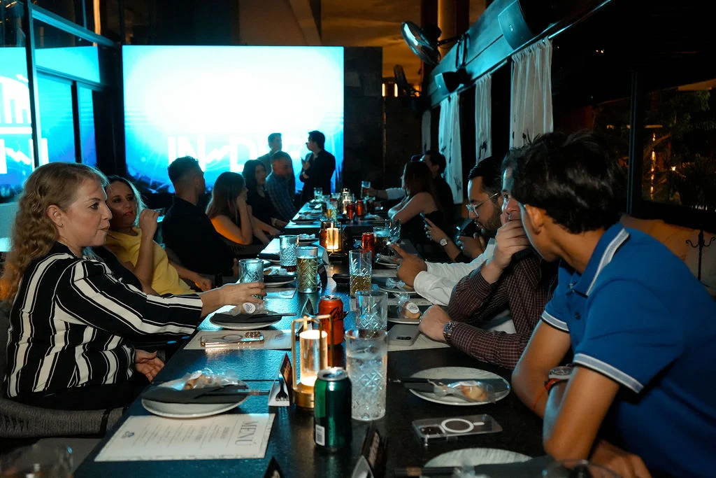 multitud de personas comiendo en mesa larga extensa de noche restaurante 