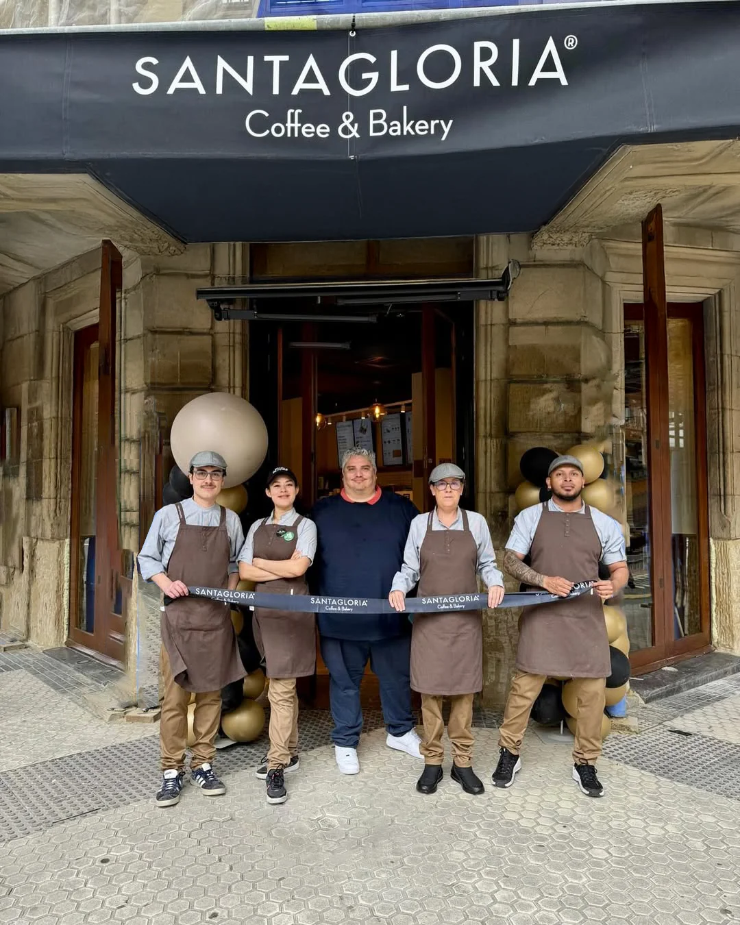 sujetos sosteniendo una cinta de apertura frente a un local de cafe