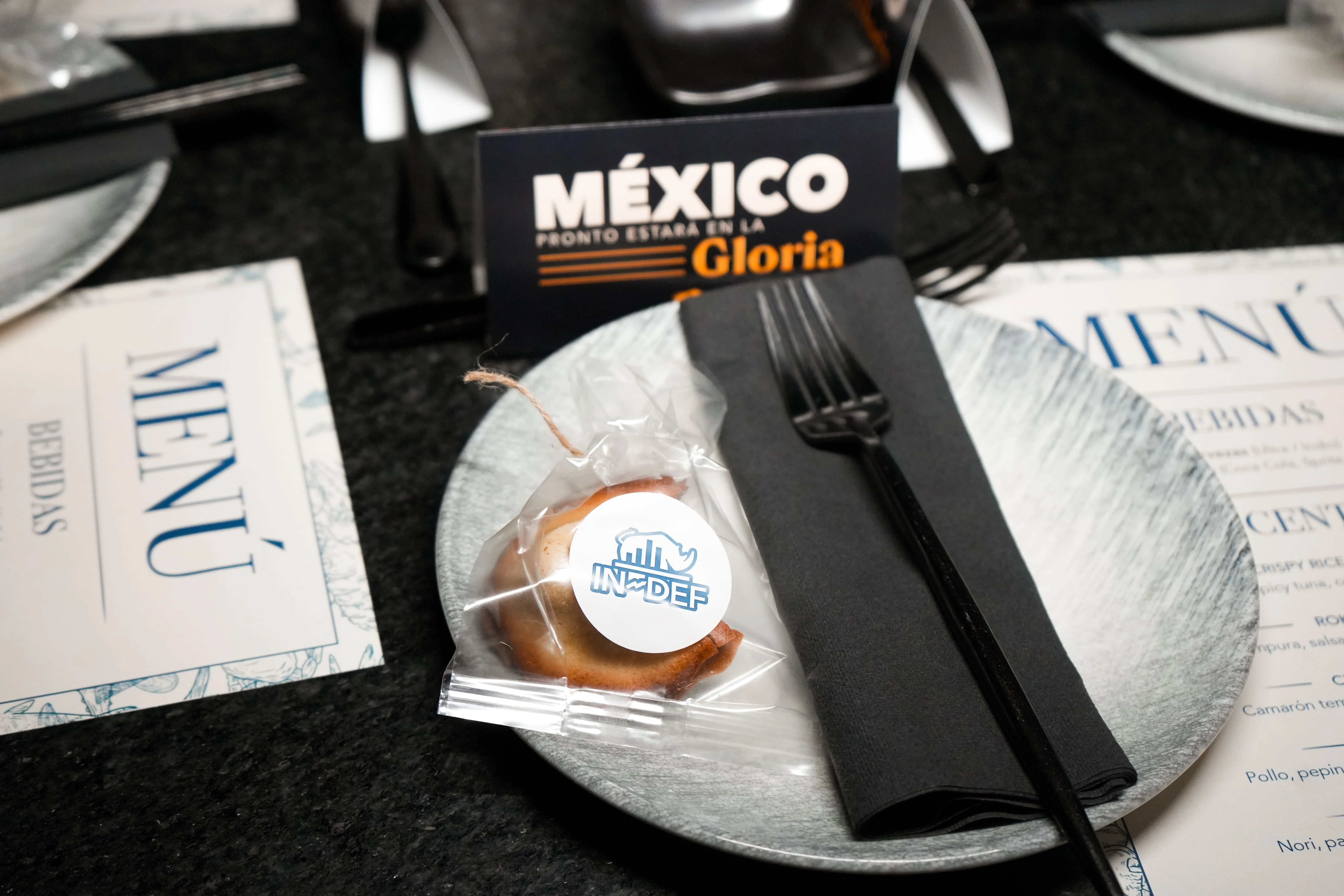 Tenedor negro y galleta de la fotunra sobre plato de porcelana blanco en una mesa con varias cartas de menú alrededor 