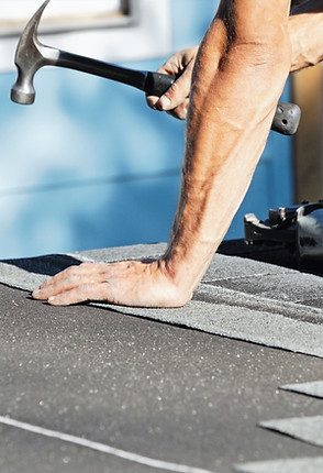 Roofer installing asphalt shingles with hammer during roof repair