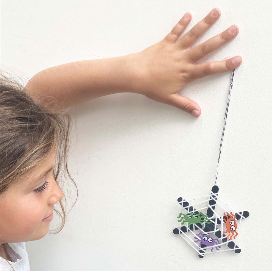 a girl holding up a finished spiders web DIY