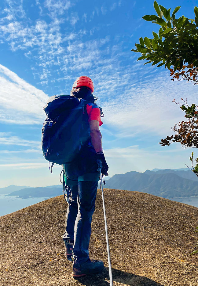 広島の瀬戸内の島々を見下ろす岩場に立つ登山ガイド