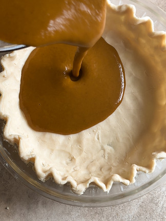 pouring pumpkin filling into pie crust