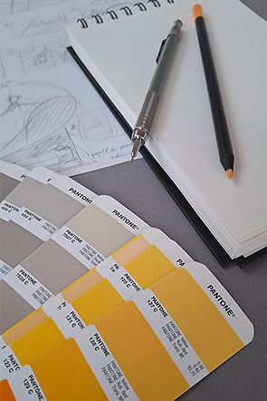 Foto do material de trabalho da Eture Design: um bloco com uma lapiseira e um lápis de cor, guia de cores e um projeto em andamento.