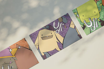 Imagem com três ilustrações de monstrinhos fofos dispostas na diagonal. As artes foram base para alguns dos rótulos da Udi. Na imagem, aparecem com o logotipo da marca, sem as informações do produto. Cada personagem tem uma paleta de cores distinta.