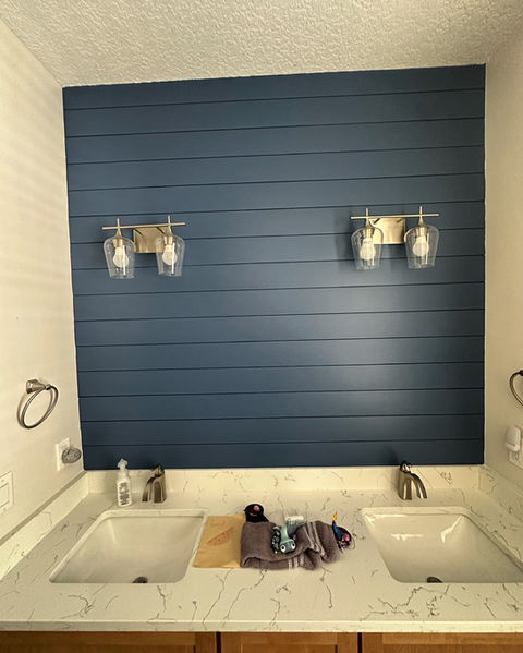 This bathroom renovation project in St. Johns, FL features a bold navy blue shiplap accent wall installed by AVP Construction JAX. Positioned behind a dual-sink vanity with white quartz countertops and modern brushed nickel fixtures, the horizontal wood paneling adds texture, color, and custom craftsmanship to the space. This contemporary bathroom design highlights AVP Construction’s expertise in bathroom accent walls, finish carpentry, and detailed interior upgrades for clients in St. Johns and Jacksonville, Florida.