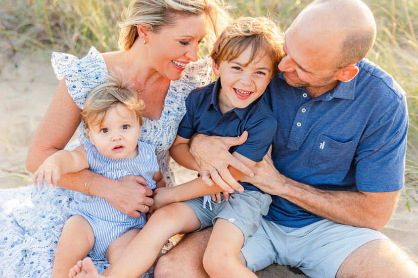 family of four tickling and laughing on the beach