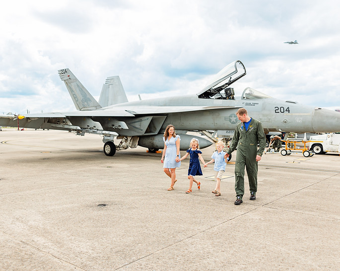 Family of four walking together hand in hand in front of an F18