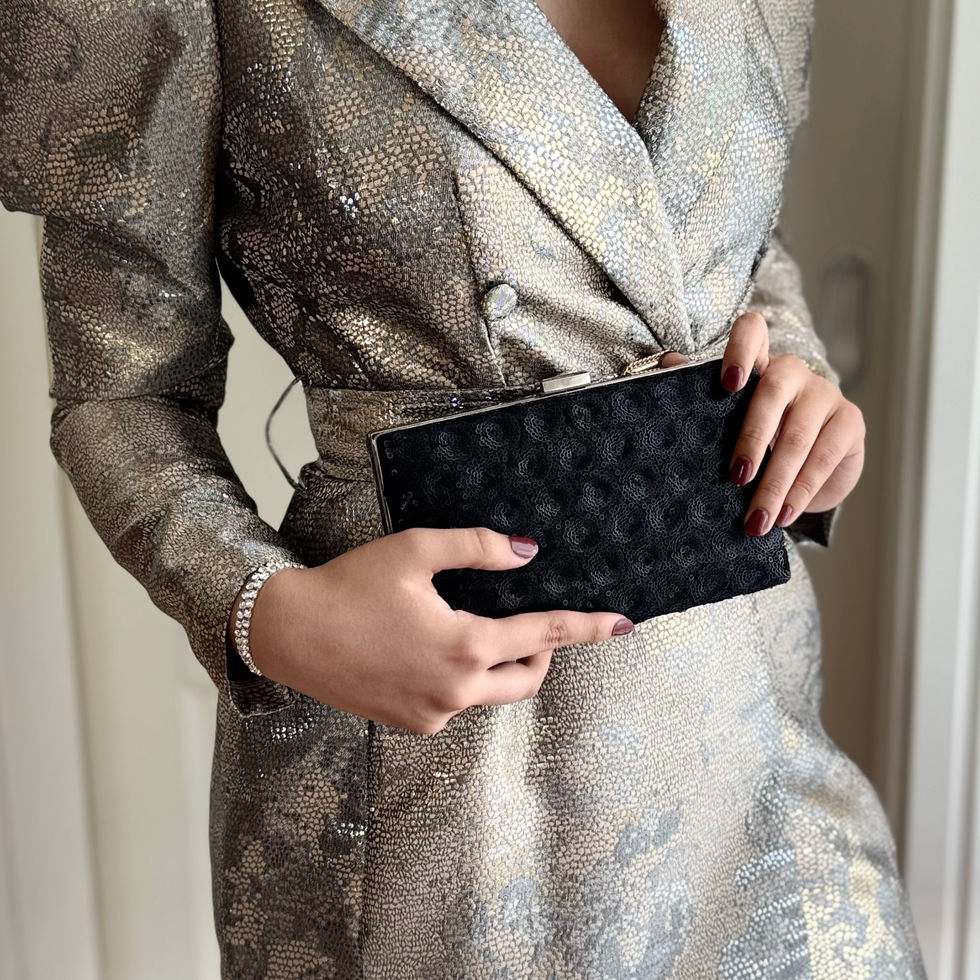 Schwarze Pailletten Clutch in der Hand einer Frau im goldenen Abendkleid.