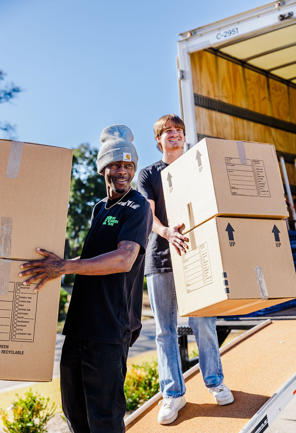 Two Big Green Box Moving team members gladly carry moving boxes.