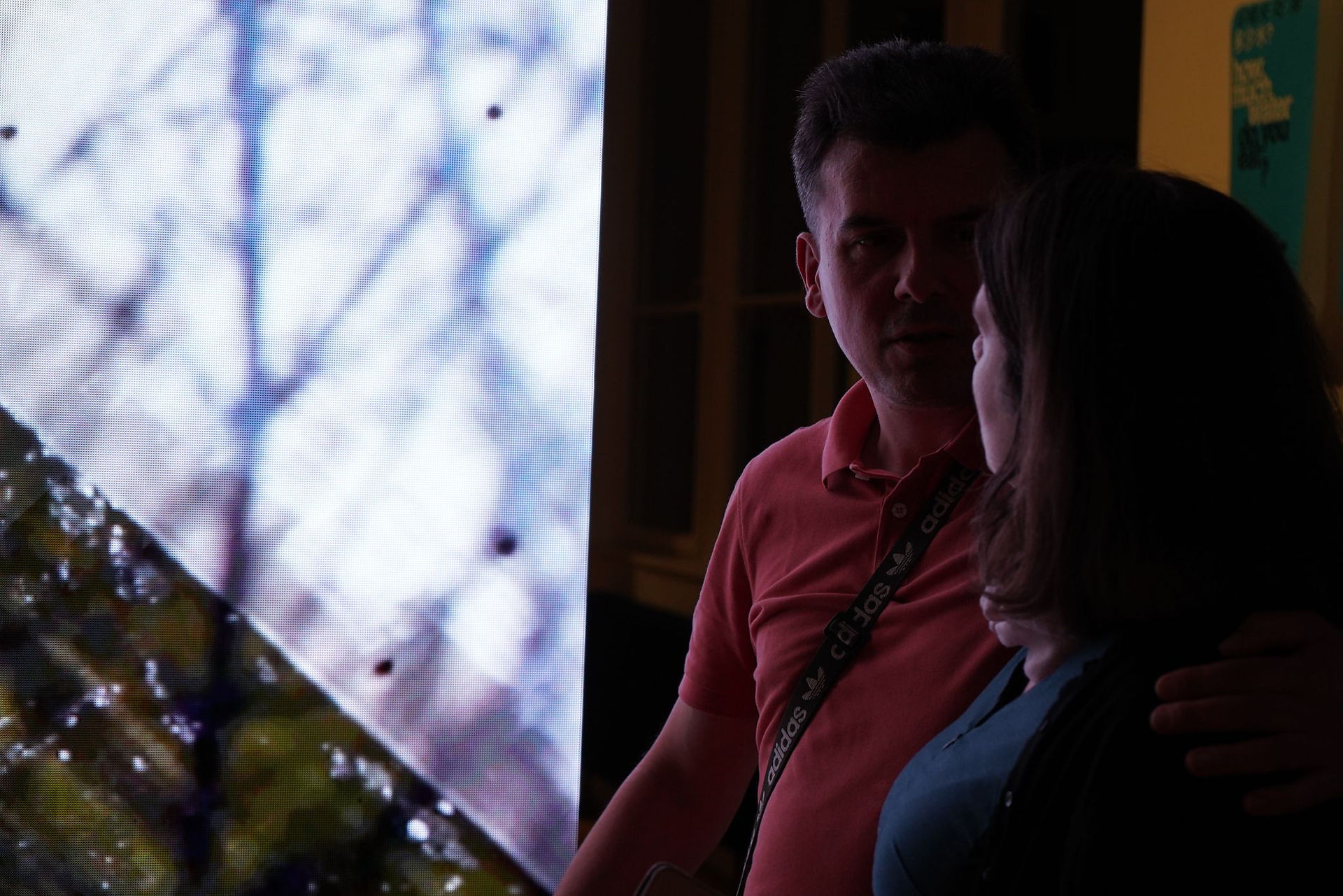 Férfi és nő beszélget a nagy képernyő előtt. 08.12. | A Love Story Budapesten.