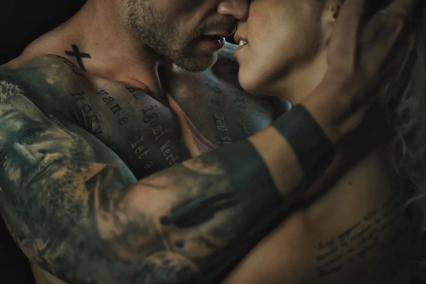 Intimate Fine Art Nude & Lifestyle Portrait – Studio Session A powerful and intimate fine art nude portrait capturing the raw connection between a couple in a professional studio setting. Blending elements of glamour and lifestyle photography, the image highlights the intricate tattoos on the male subject's skin while focusing on the emotional intensity and physical closeness of the pair. The moody, dramatic lighting accentuates the textures and the romantic atmosphere, creating a timeless artistic composition. Photographed by Norbert Bánhalmi Category: Fine Art Nude / Glamour / Lifestyle