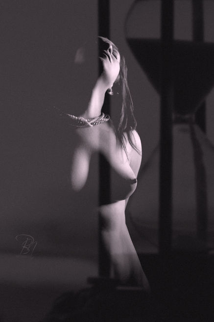 Árnyékban táncoló nő, homokóra háttérrel, a pillanatok múlása, fekete-fehér fotó.