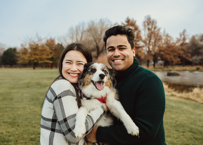 Couple with aussie dog. Setting is fall in the park. 