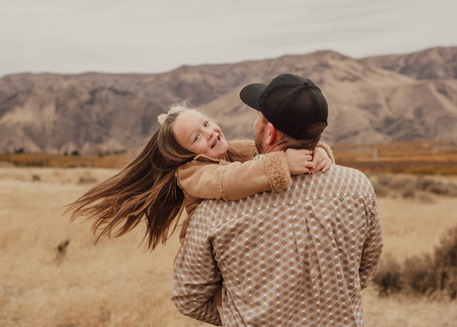 Father swings daughter around. Daughter is laughing. 