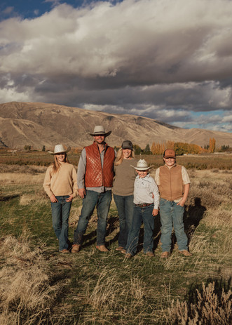 Family of 5 in country western outfits in front of mountain. 