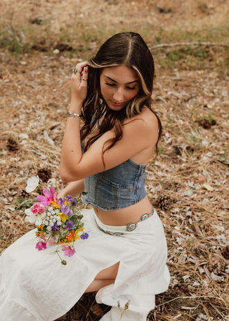 Woman holding flowers looking downward over her shoulder. 