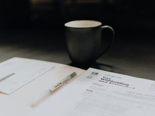 Tax forms and a pen on a desk beside a dark mug, with a page titled Tax withholding.