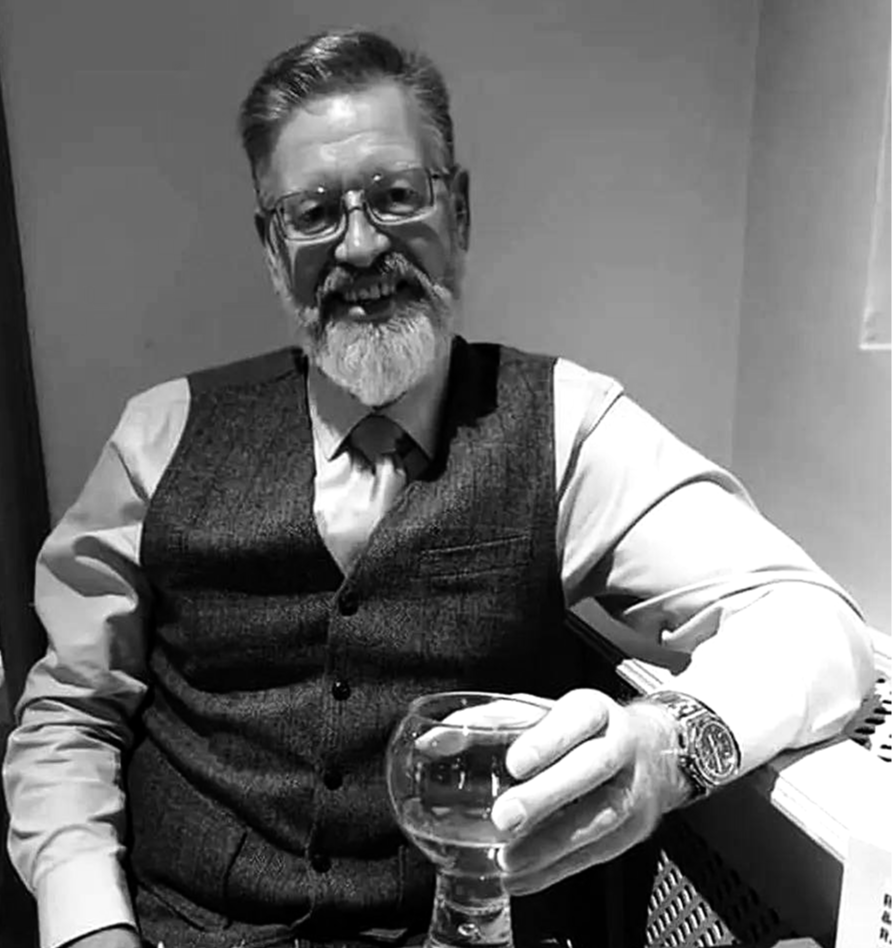 Smiling man with glasses and beard holding a glass drink