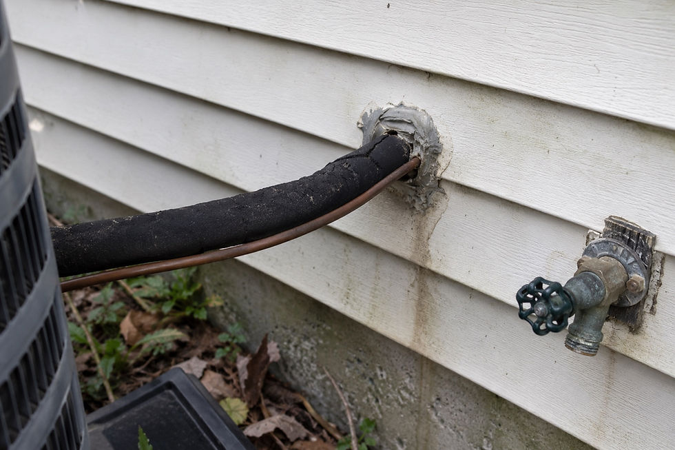 Refrigerant lines entering the wall through the siding, sealed at the penetration