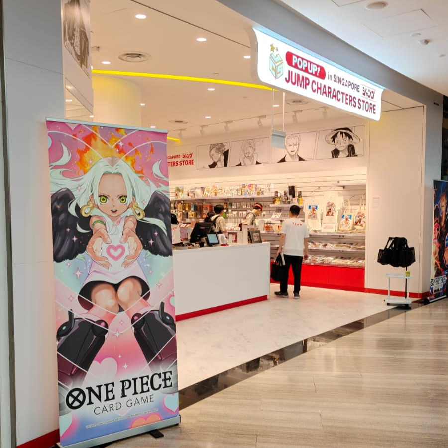 Anime-themed pop-up store with colorful "One Piece" banner in foreground. People inside browse merchandise and character art lines the walls.