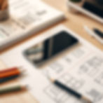 a phone on a desk with paper with drawings on the like home planning.jpg