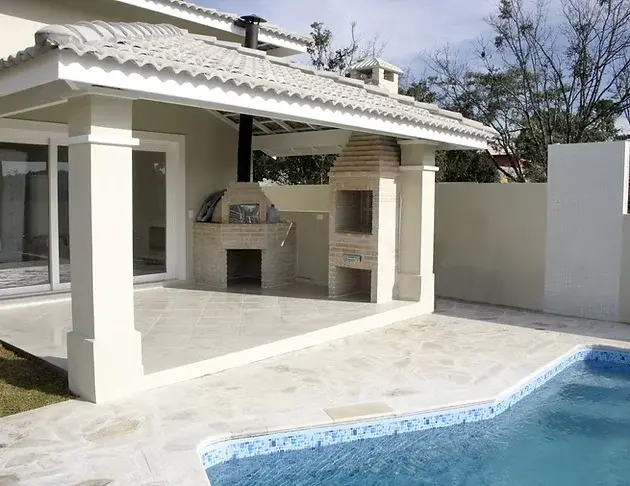 Detached backyard structure with a covered patio, built-in barbecue, and pool area