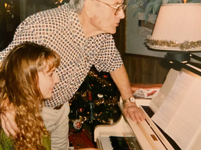 grandfather and granddaughter at the piano in a welcoming living room