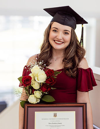A Female University Graduate standing in the MUN Science building with her diploma with flowers. .