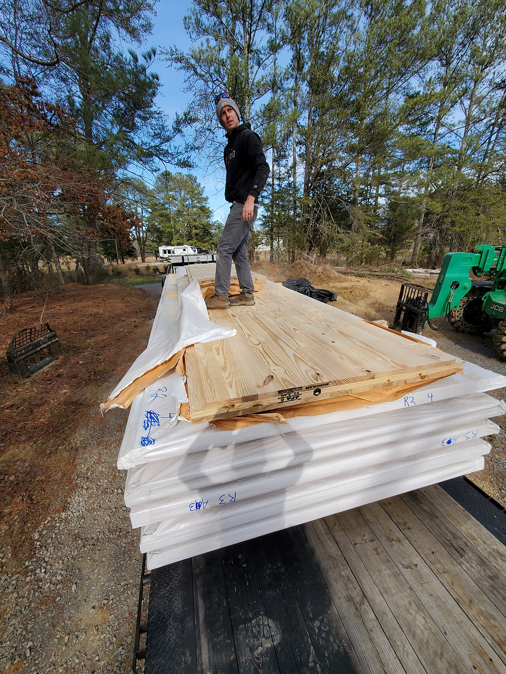 David Hammond stands on CLT boards that were delivered in the woods for cabin project.