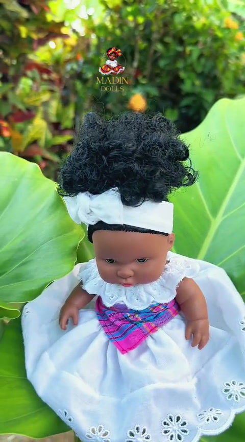 vidéo poupée artisanale de 25 cm, habillée d’une ceinture madras rose et bleue et d’une jupe blanche brodée