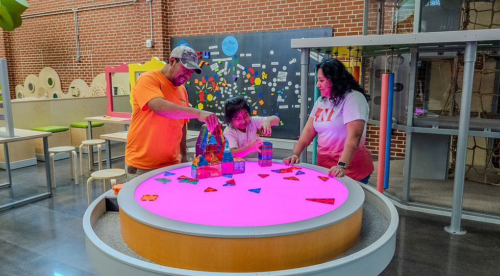 Mesa de exhibición interactiva con familias dentro del Centro de Descubrimiento EPIC.